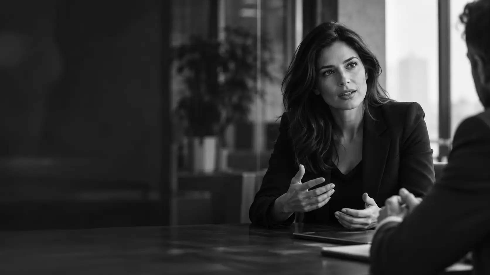 A sales consultant speaking thoughtfully with a client in a modern office, in black and white.